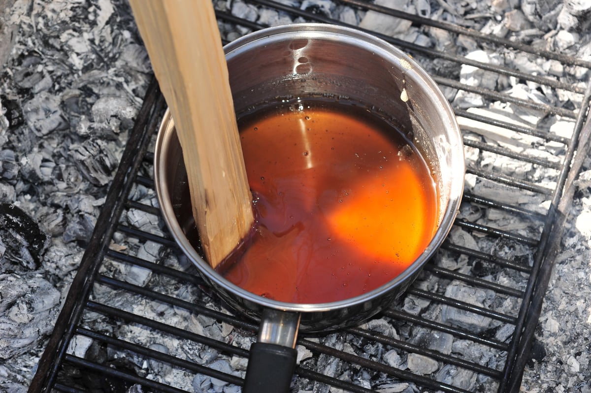 A pot of maple syrup boiling over an open wood fire